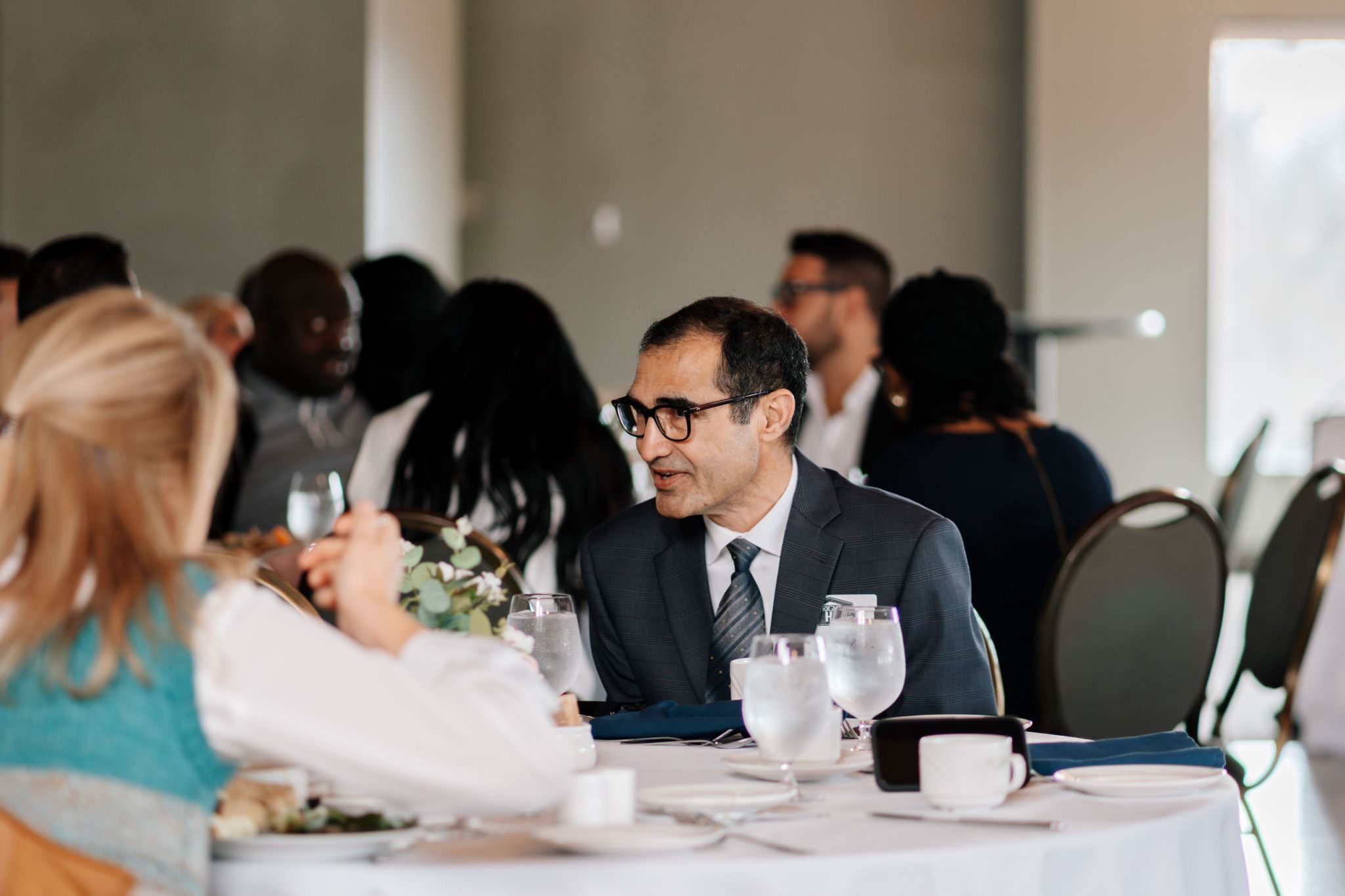 Ash Choudhry speaking with clients at a community event